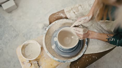 top view on pottery wheel and artist hands creating ceramic bowl, tracking shot, slow motion