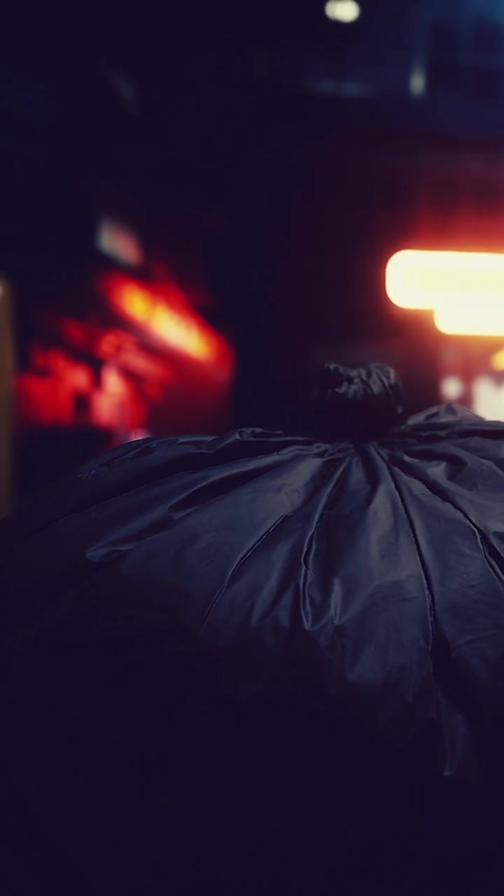 Person carrying a large bag near bright neon lights at night
