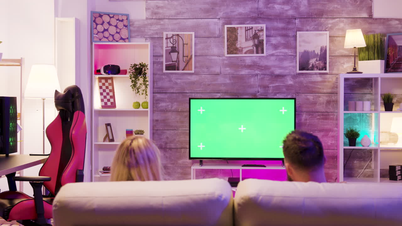 Couple watching TV with green screen in living room