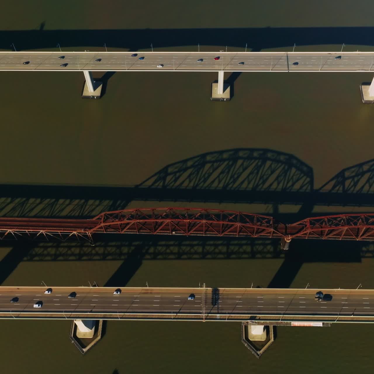 Railway bridge between automobile bridges in Martinez, California, USA. Bird's eye view on the bridges at backdrop of dark water