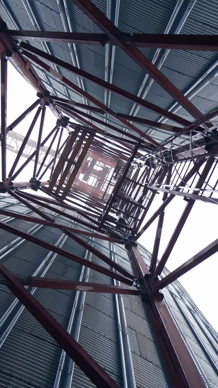 Metal towers on industrial plant.. Steel construction on a modern agricultural factory with grain elevators on sky background. Vertical video