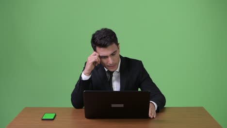 joven y guapo hombre de negocios hispano contra un fondo verde