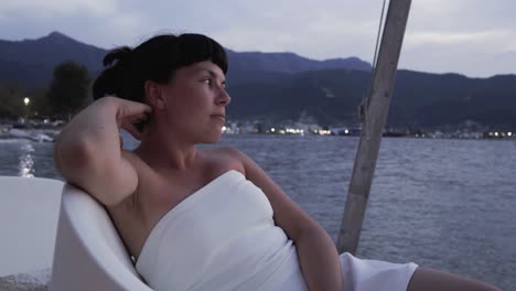 Girl-in-a-white-dress-enjoys-the-beach-bar-ambiance,-contemplating-the-summer-sea