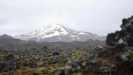 Volcanic-Rock-in-Front-of-a-Snowy-Iceland-Mountain-in-Slow-Motion