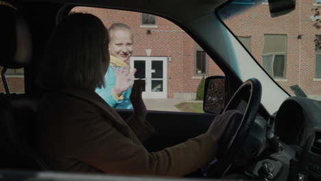 A-woman-brings-a-child-to-school,-a-girl-gets-out-of-a-car-and-runs-to-the-building-of-a-typical-American-school.