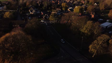 Englische-Dorfstraße,-Umgeben-Von-Herbstbäumen,-Luftbild,-Das-Zur-Goldenen-Stunde-In-Die-Ländliche-Nachbarschaft-Kippt