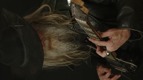 vertical format: bearded man in black stetson plays electric guitar