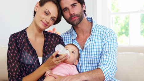 Cute-couple-sitting-on-a-sofa-and-bottle-feeding-to-their-baby