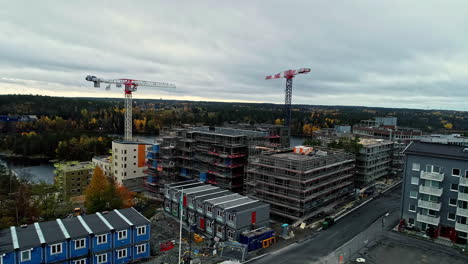 construction site with unfinished buildings and tower cranes near a river