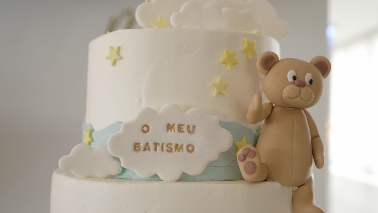 white baptism cake decorated with fondant bear, yellow stars, and cloud reading 'o meu batismo'