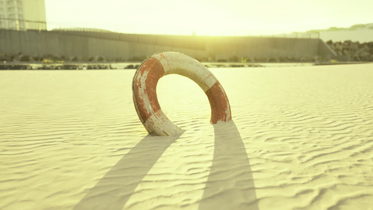 Lifebuoy resting on the sandy beach during golden hour at sunset