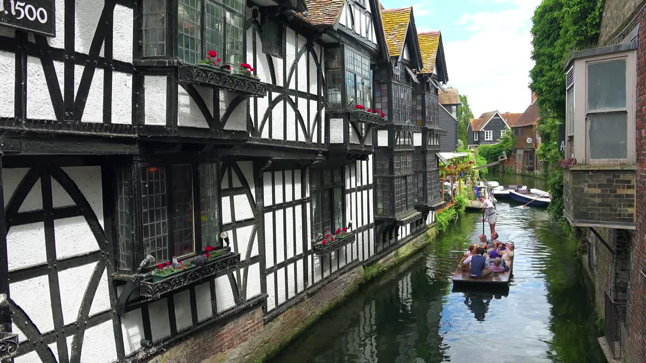 캔터베리 켄트 잉글랜드의 아름다운 건축물로 둘러싸인 운하 아래로 보트가 노를 젓고 있습니다.