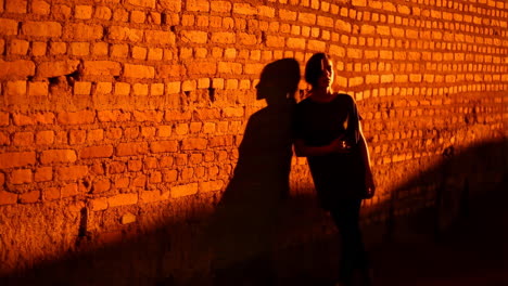 woman leaning against a brick wall in sunset lighting