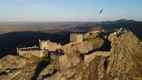 un dron rodea el castillo de marvao mientras un rebaño lo sigue durante la puesta de sol