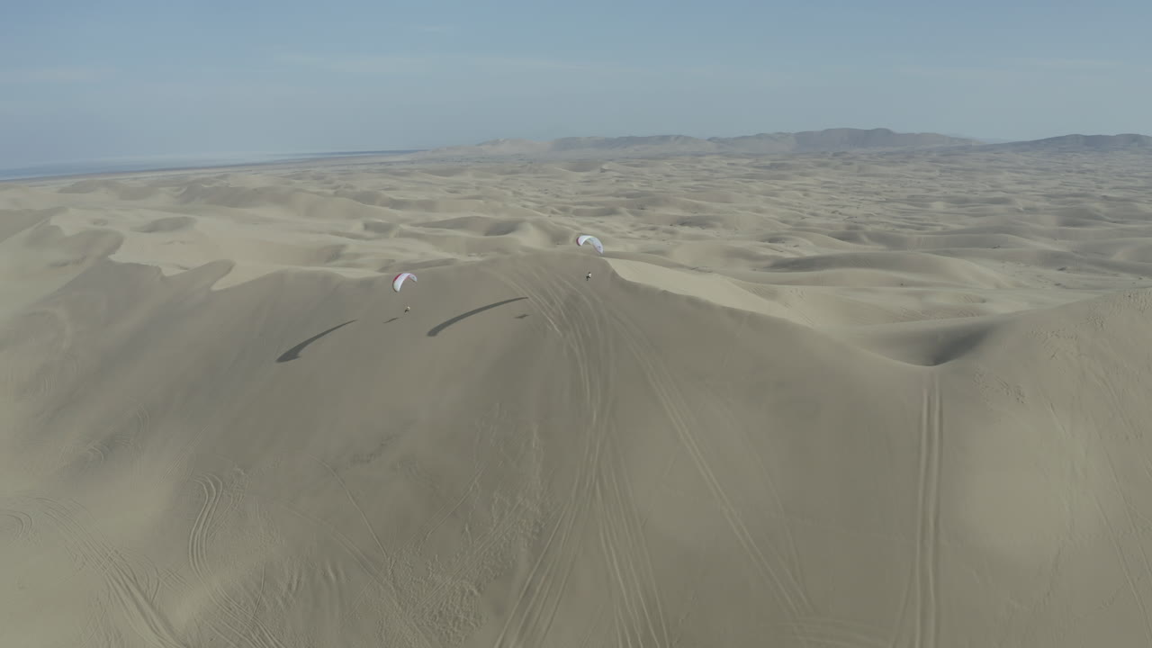 Soaring paragliders over vast desert sand dunes in Iran, captured from above