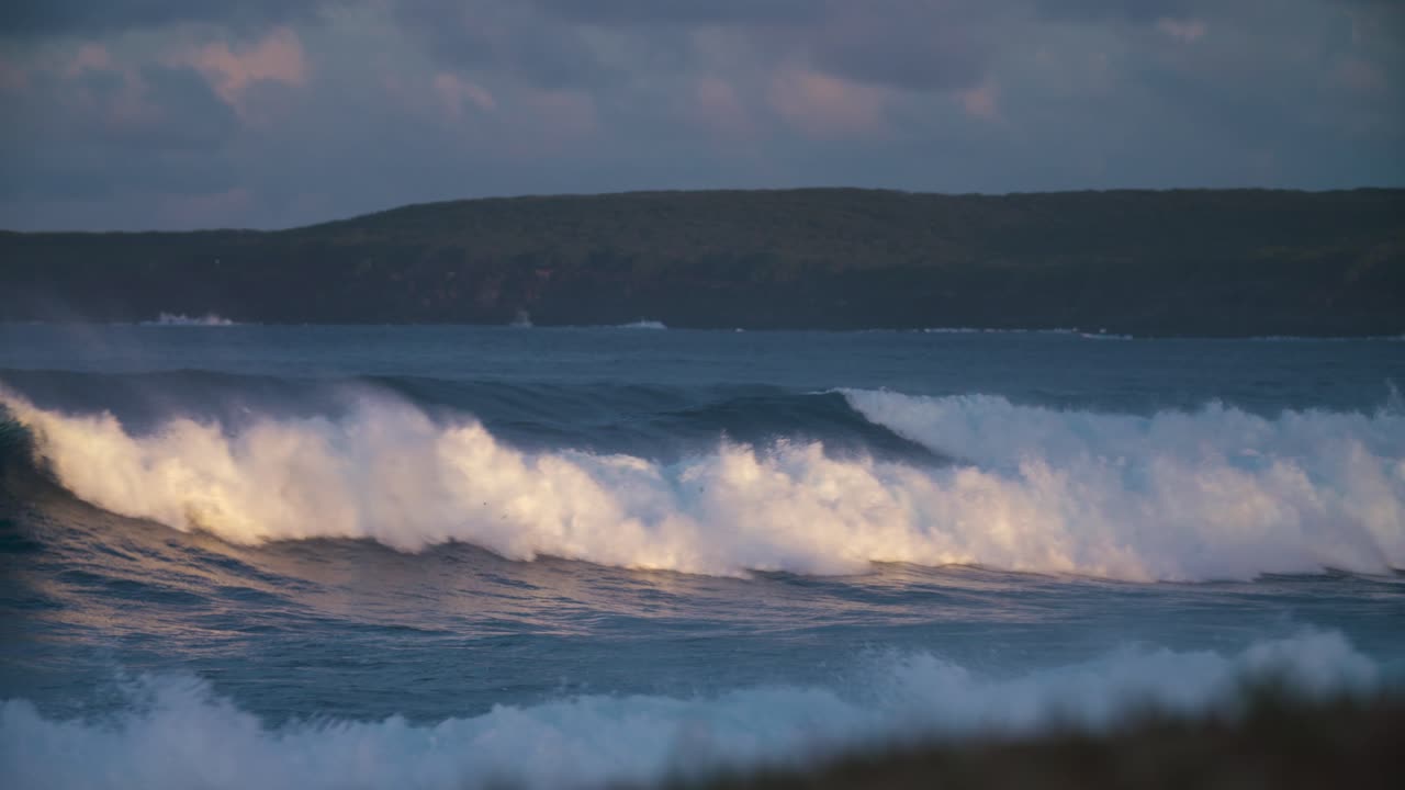 las olas del océano se deslizan hacia la costa con luz dorada en cámara lenta