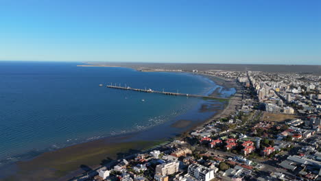 panorama drone view of the muelle comandante luis piedra buena pier and coastal town with blue ocean, patagonia chubut, puerto madryn, argentina.