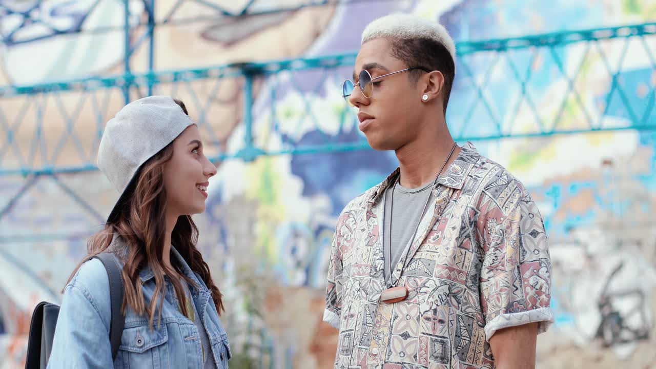 모자를 쓰고 거리에서 그녀의 남자 친구와 이야기하는 hipster 스타일의 백인 여자