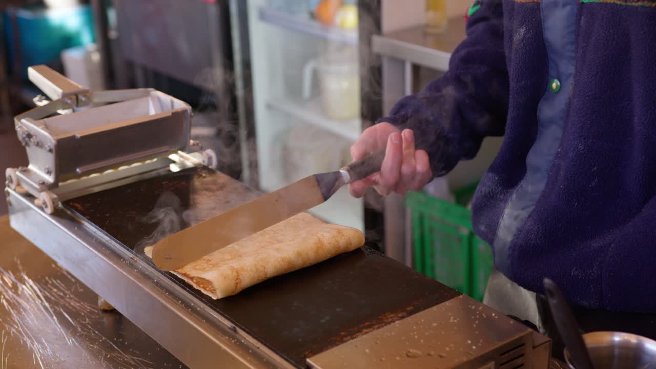 primer plano de la persona que hace panqueques franceses tradicionales en un plato caliente mientras sale humo