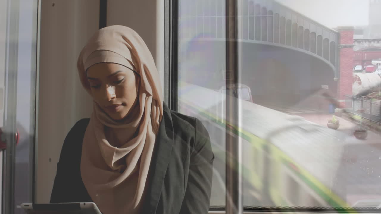Animation of asian woman in hijab using tablet over cityscape