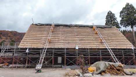 scaffolding supports workers restoring a rustic gasshō-zukuri style roof in shirakawago. pan right