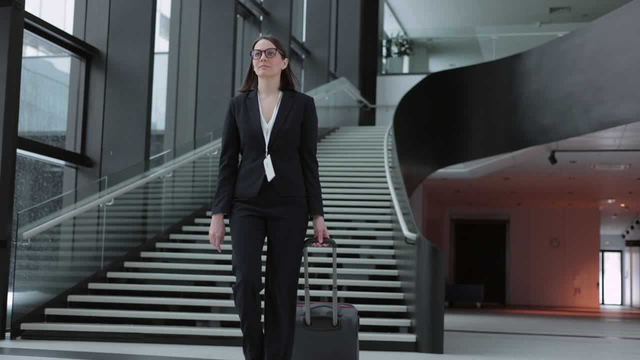 business woman in a business suit with a suitcase walks through the airport or business center and talks on the phone. a European confident woman