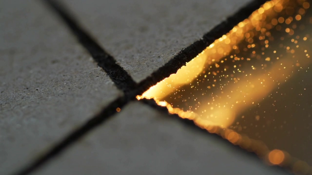 Camera shifting focus, narrow golden seam revealing glittering particles on tiled floor grout cross