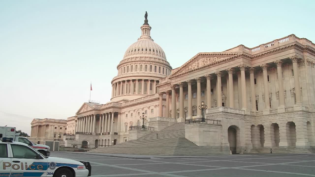 el edificio del capitolio está enmarcado en una luz tenue con un coche de policía en primer plano