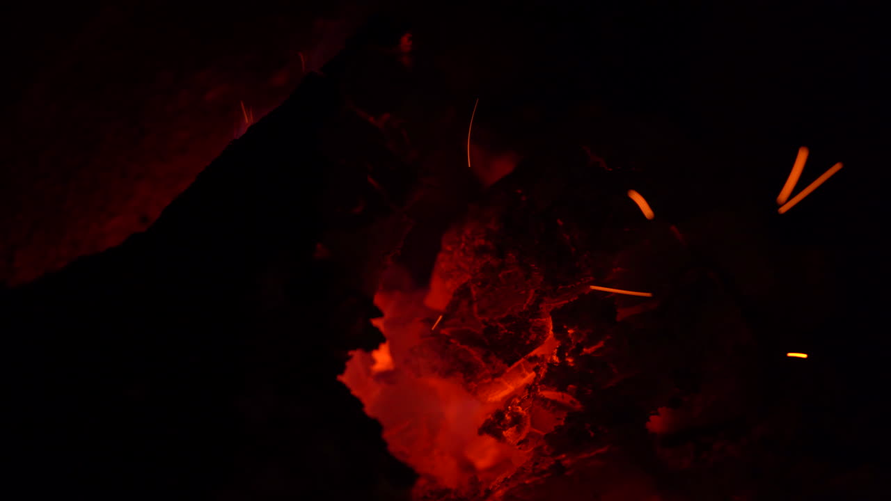 Orange and black glowing embers in a fire with little flames, close up