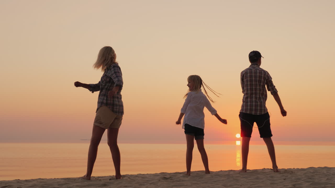 두 자녀를 둔 젊은 어머니가 선셋 컴에서 해변에서 세련된 춤 동작을 가르치고 있습니다.
