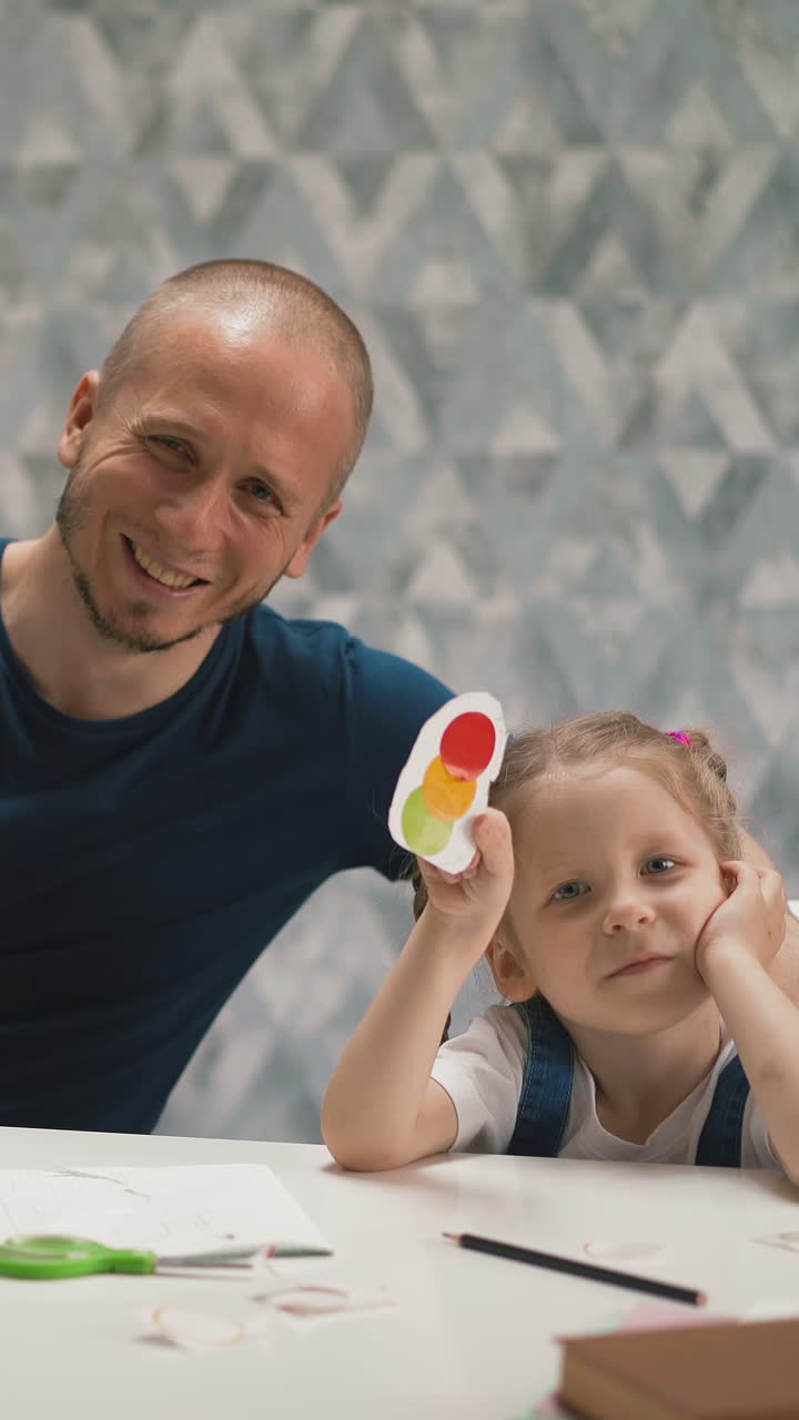 bloggers dad and young daughter, show example of online learning at home, demonstrate on camera multicolored stickers, homework result, smile