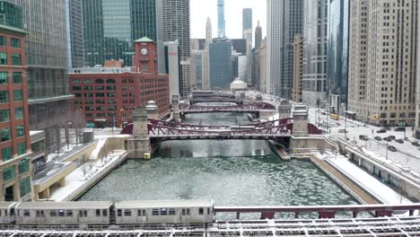 amazing aerial establishing shot, subway train over frozen chicago river, winter