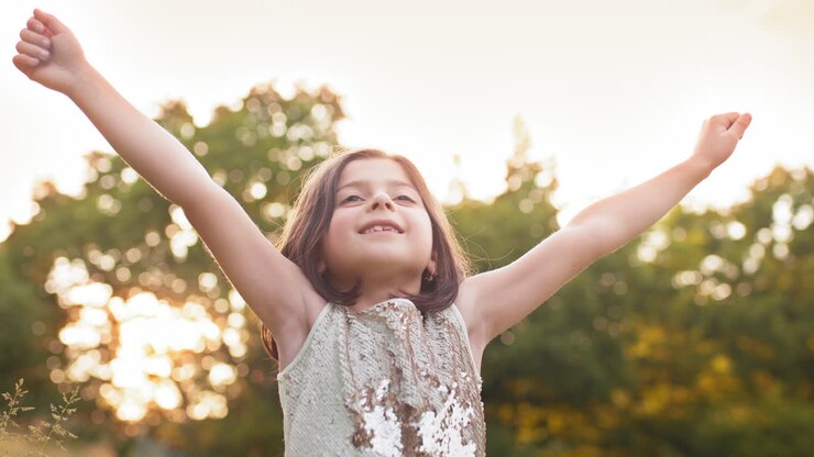 Ragazza sorridente in un parco al tramonto.