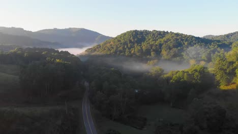 4k drone video flying above trees along mountain road in smoky mountains near asheville, nc on foggy morning