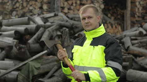 Man-woodcutter-lumberjack-with-small-axe.-Sawn-logs,-firewood-background.-Asks-to-follow-him