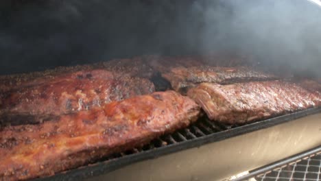 close up of smoke blowing over racks of ribs in an off set smoker