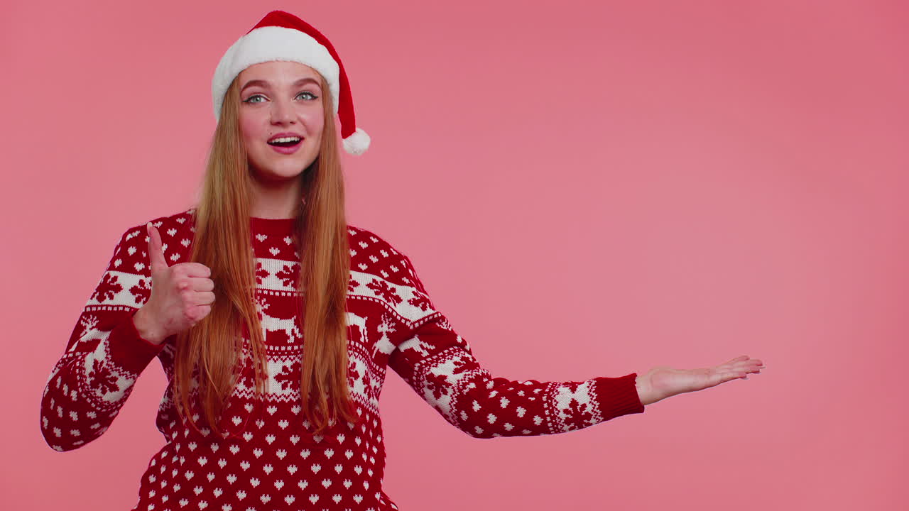 mujer lleva suéter de año nuevo rojo ciervo mostrando los pulgares hacia arriba y señalando en el espacio de publicidad en blanco