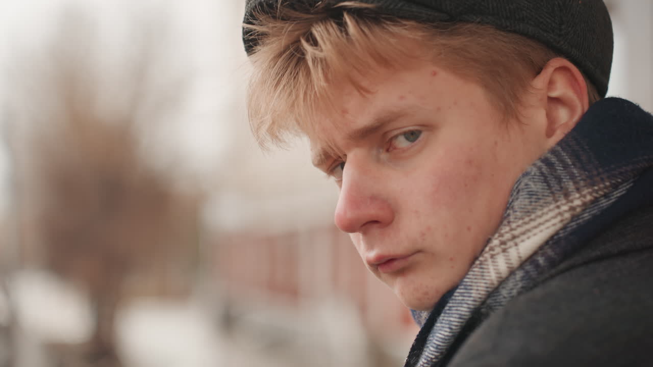 Tvůrce v kabátě zamyšleně hledí. Malířská postava v zimním oblečení rozjímá nad okolím. Mladý člověk oblečený na zimu zamyšleně hledí při procházce po městském chodníku.