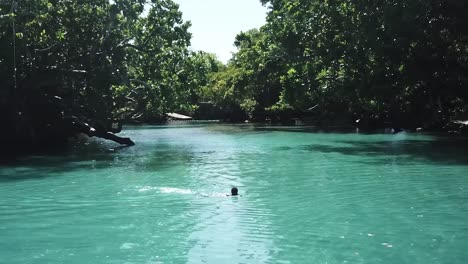 drohne fliegt tief über person, die in der atemberaubenden blauen lagune schwimmt