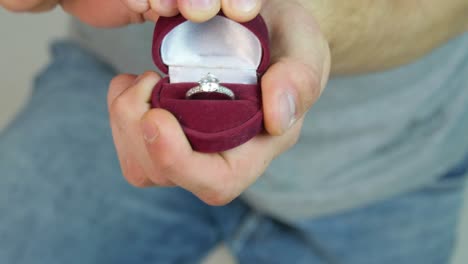 man holding engagement ring in a red box