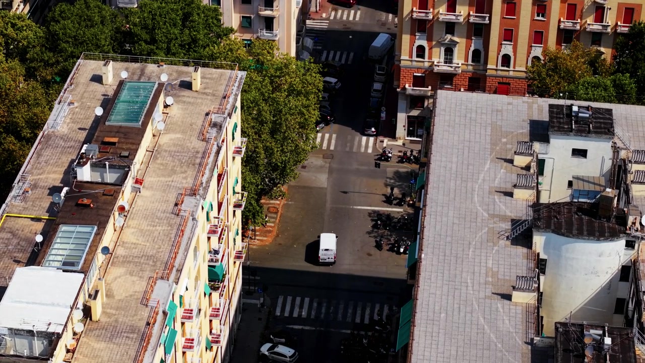 Aerial view of city street with moving traffic between colorful buildings in Genoa