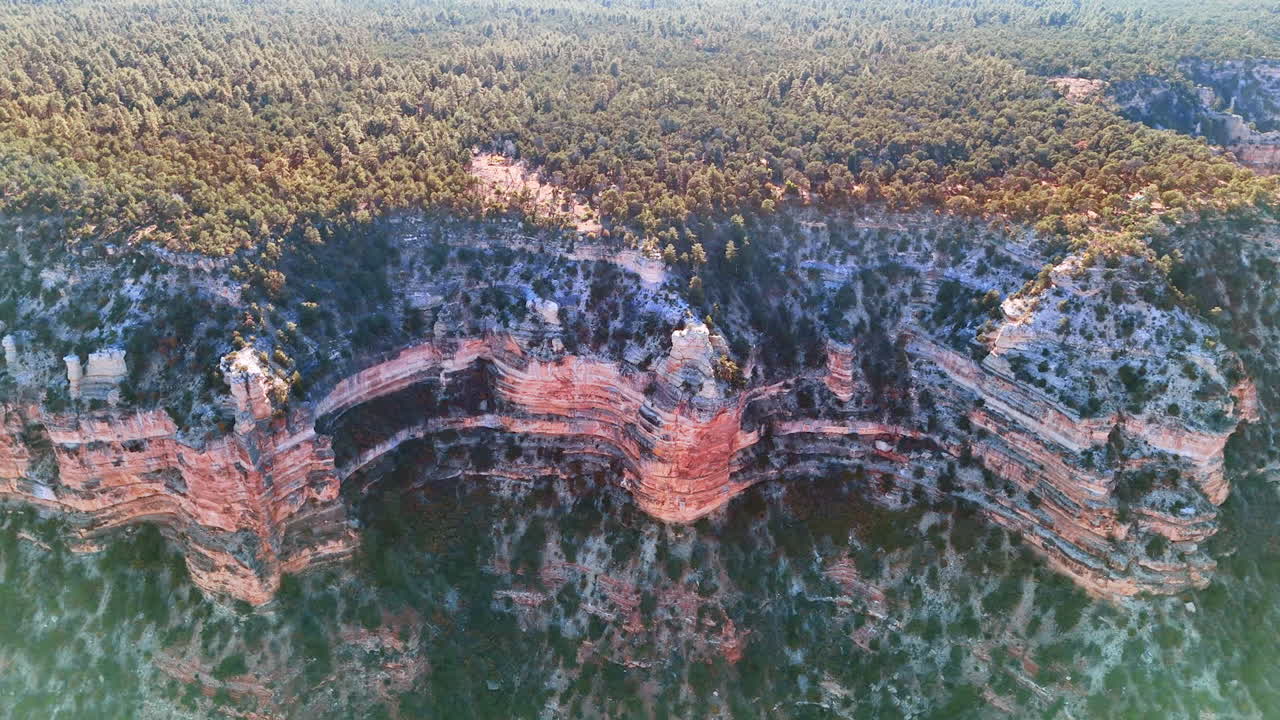 Approaching the rocks covered with scarce vegetation. Lush greenery grows on the plain on top of the rocks. The Grand Canyon National Park, Arizona, USA. Aerial view