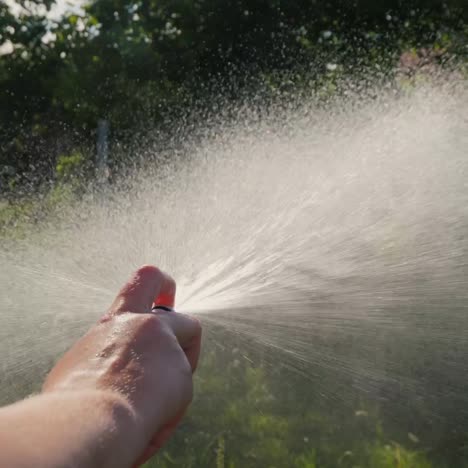 la mano del jardinero vierte una manguera de jardín con un difusor