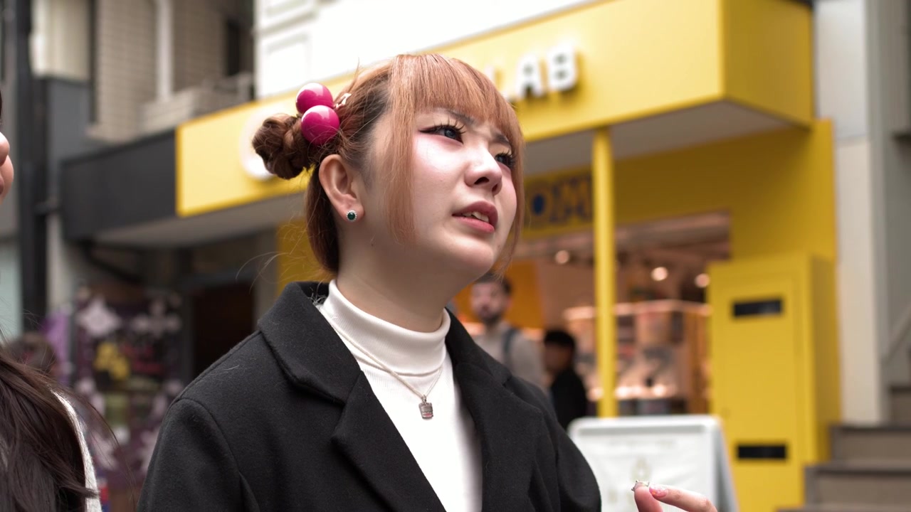 Una giovane donna elegante parla in modo espressivo mentre si trova su una strada affollata ad Harajuku, Tokyo
