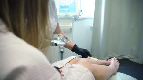 mujer recibiendo tratamiento de depilación de piernas en un spa