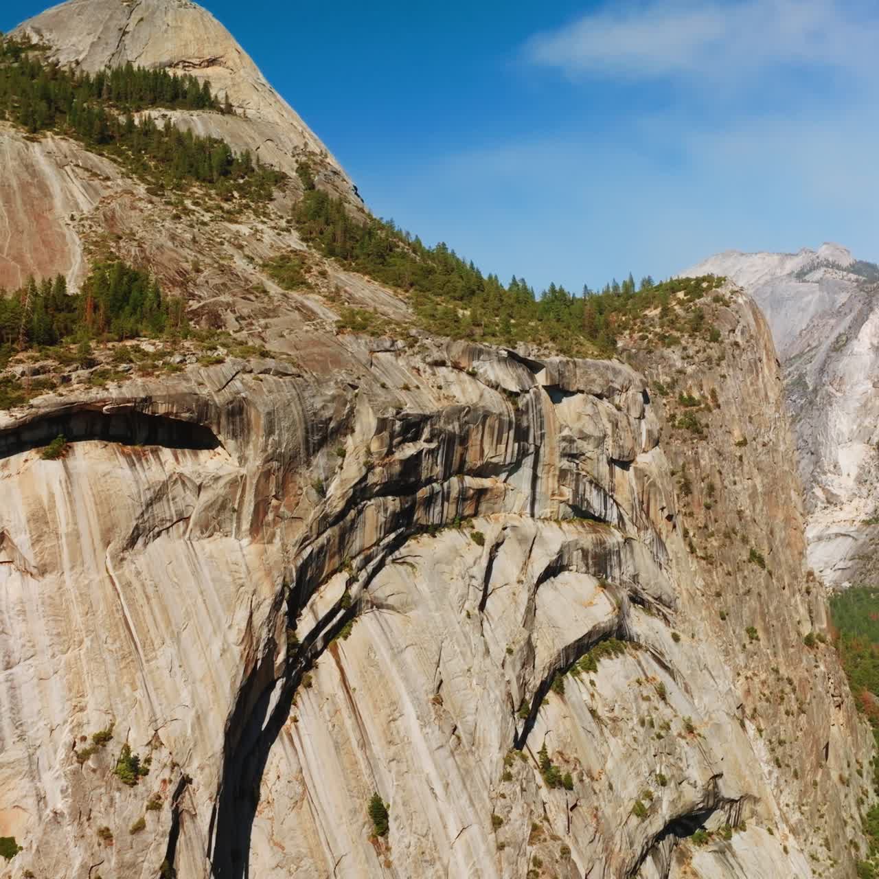 Steep grey cliffs of Yosemite National Park, California, USA on sunny daytime. Rocky scenery with pine woods from aerial view