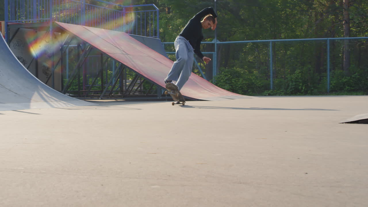 Young Man Skating on Two Wheels in Skatepark