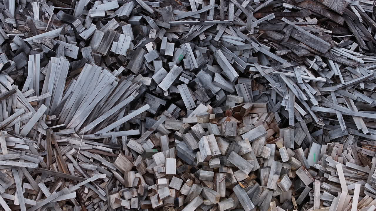 Top down aerial footage panning across piles of various wood materials.