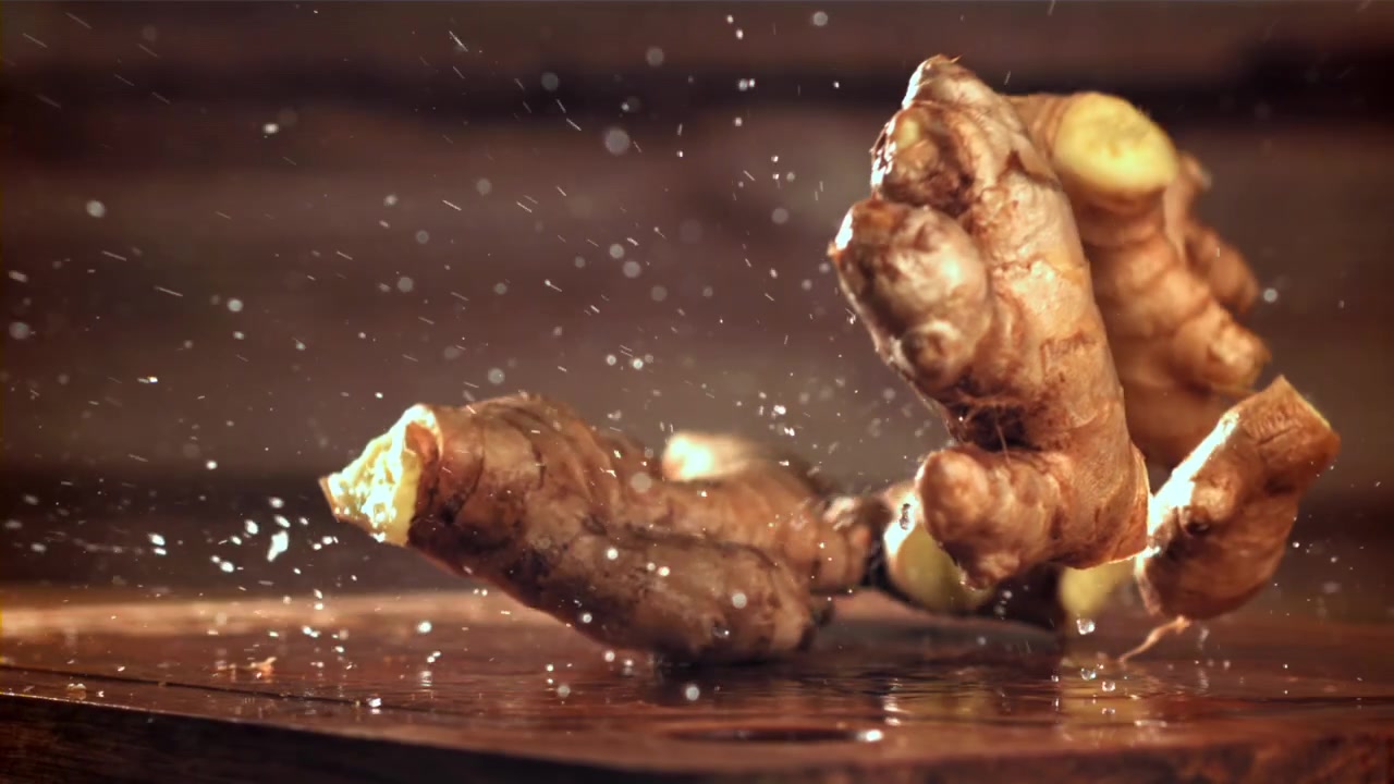 Fresh Ginger Roots Falling onto a Wet Wooden Surface in Slow Motion