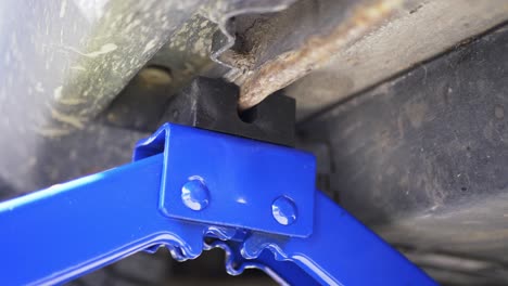 Hydraulic-car-jack-adjustable-scissor-lift-under-vehicle-for-maintenance-inspection-close-up